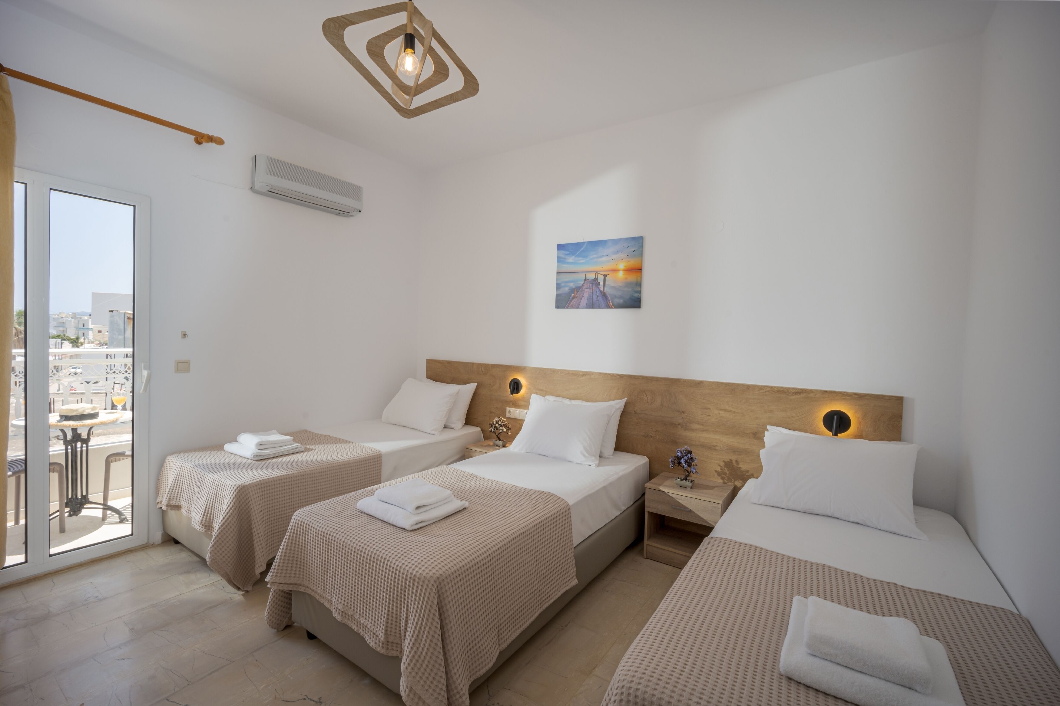 Habitación de hotel con dos camas individuales, cabecero de madera, un cuadro y vistas a través de un ventanal.