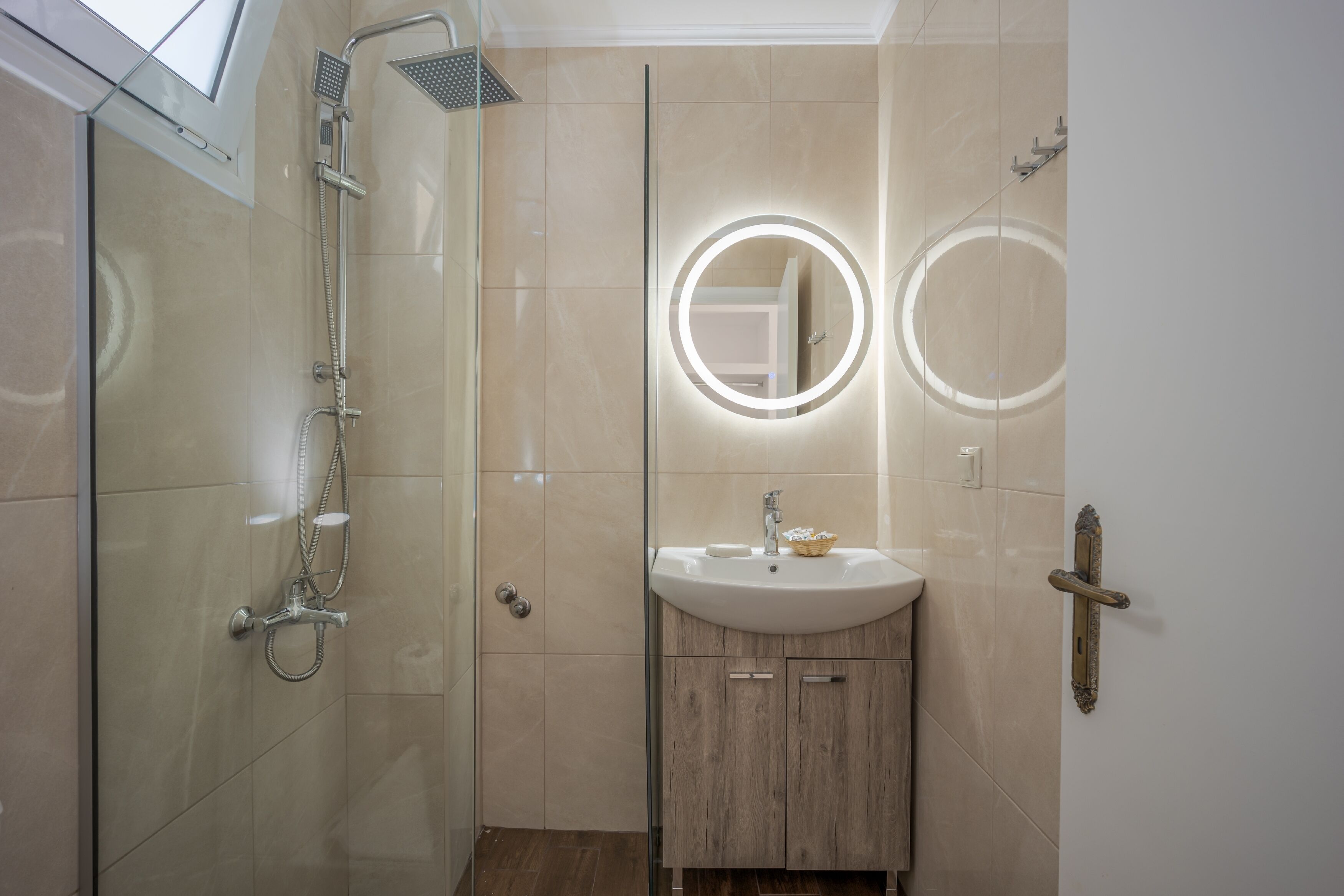 Ein modernes Badezimmer mit einer Duschkabine, einem Waschtisch und zwei beleuchteten Spiegeln.