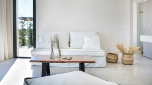A modern living room with a white sofa, a wooden coffee table, and two woven baskets on the floor. - Villa Dimelisa - Modern Villa with breathtaking views of the Ionian Sea (Argostoli)