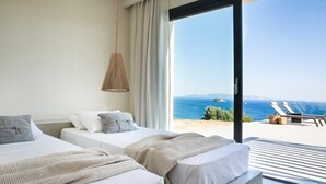 A modern hotel room with two beds, a large window with a view of the sea, and a balcony with lounge chairs. - Villa Dimelisa - Modern Villa with breathtaking views of the Ionian Sea (Argostoli)