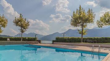 Una piscina con vista sulle montagne, sugli alberi e su un cielo sereno.