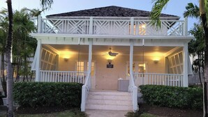 A two-story building with a covered porch, a staircase leading to the entrance, and a sign indicating a water fountain. - Beautiful  4BR villa w/pool in St James, Porters.  5 min walk to gorgeous beach. (Porters)