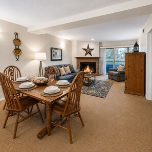 A dining area with a wooden table and chairs, a sofa, a fireplace, and a large star decoration on the wall. - 103 Empire Coalition Escape! Cozy Condo Close To Resort! 2 Bedroom Condo by RedAwning (Park City)