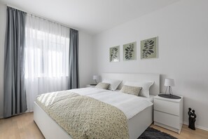 A modern bedroom with a large bed, bedside tables, and decorative wall art.