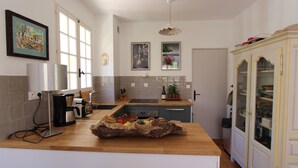 Eine moderne Küche mit Holzarbeitsplatte, einer Kaffeemaschine, einem Wasserkocher und einem dekorativen Holzscheit-Arrangement.