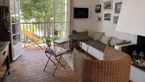 Ein gemütliches Wohnzimmer mit einer Couch, einem Korbstuhl, einem kleinen Tisch und einem Fernseher.