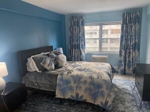 Cozy retreat with a comfortable bed, nightstand, and radiator, set against a serene backdrop.