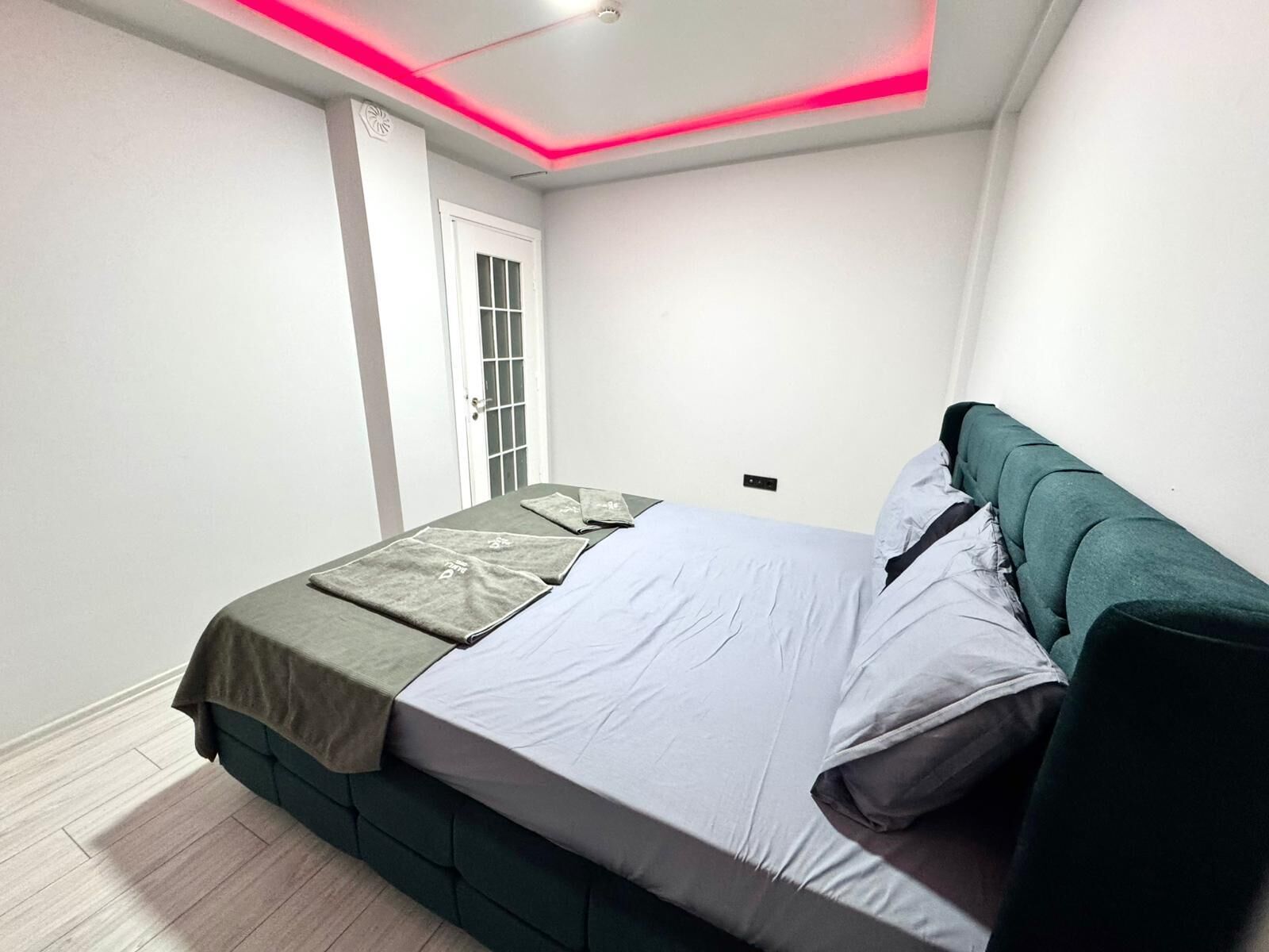 Una camera da letto ordinata con un letto, cuscini e una testiera verde.