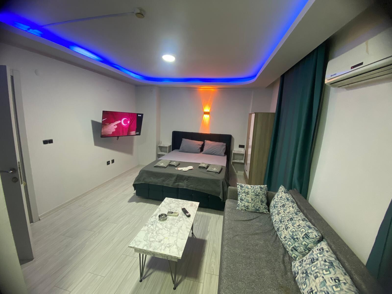 Ein modernes Hotelzimmer mit Bett, einer Couch, einem Fernseher und einer Deckenleuchte.