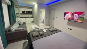 Une chambre d’hôtel moderne, équipée d’un canapé, d’un lit, d’une petite table et d’un téléviseur fixé au mur.