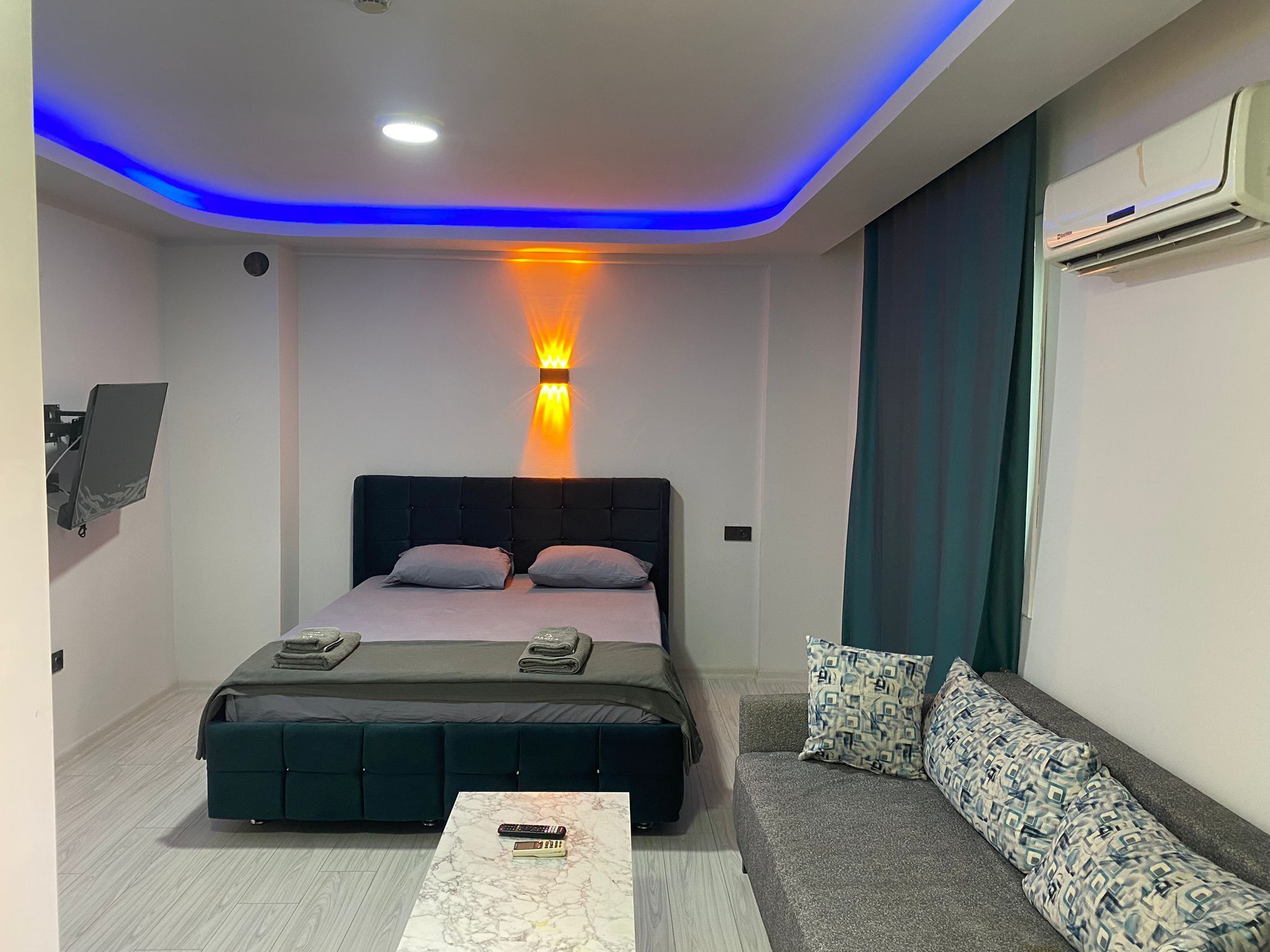 A modern bedroom with a bed, bedside table, and a sofa.
