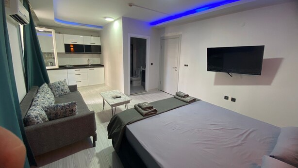 Une chambre moderne avec un grand lit, un canapé, une petite table et un téléviseur fixé au mur.