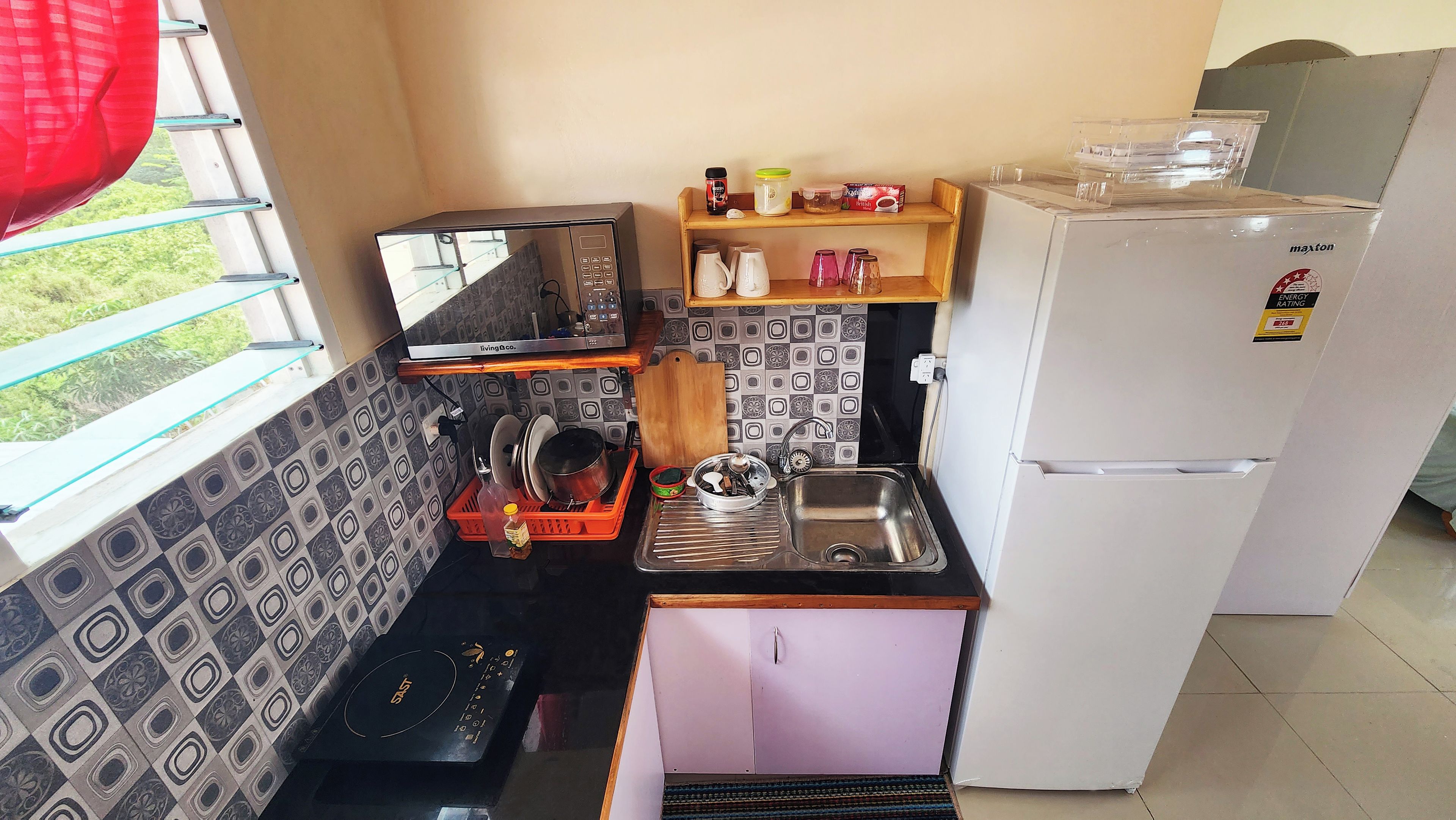 Cozinha compacta com micro-ondas integrado, pia e geladeira.