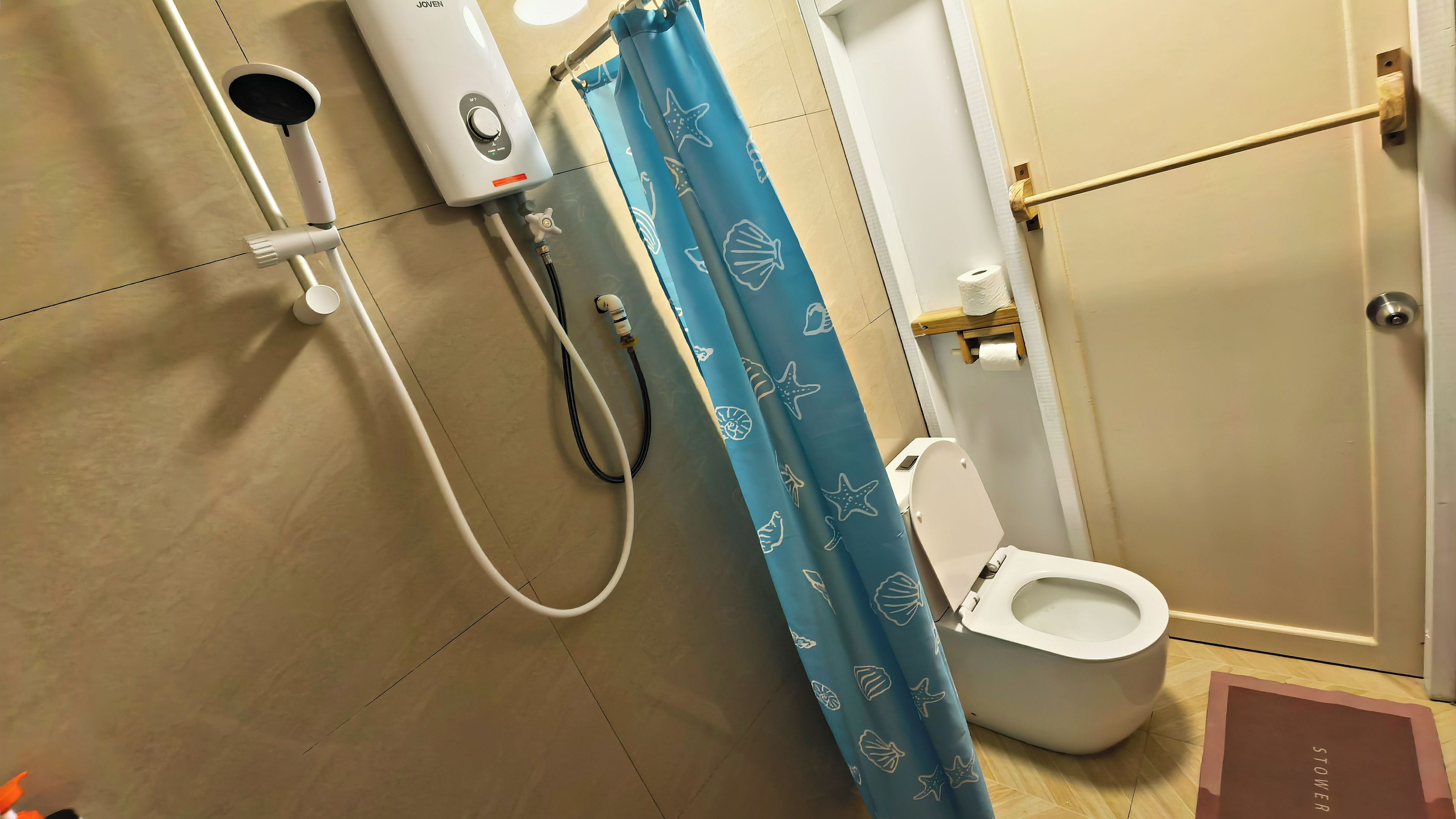 Baño con inodoro, ducha y cortina de baño azul con motivos de criaturas marinas.