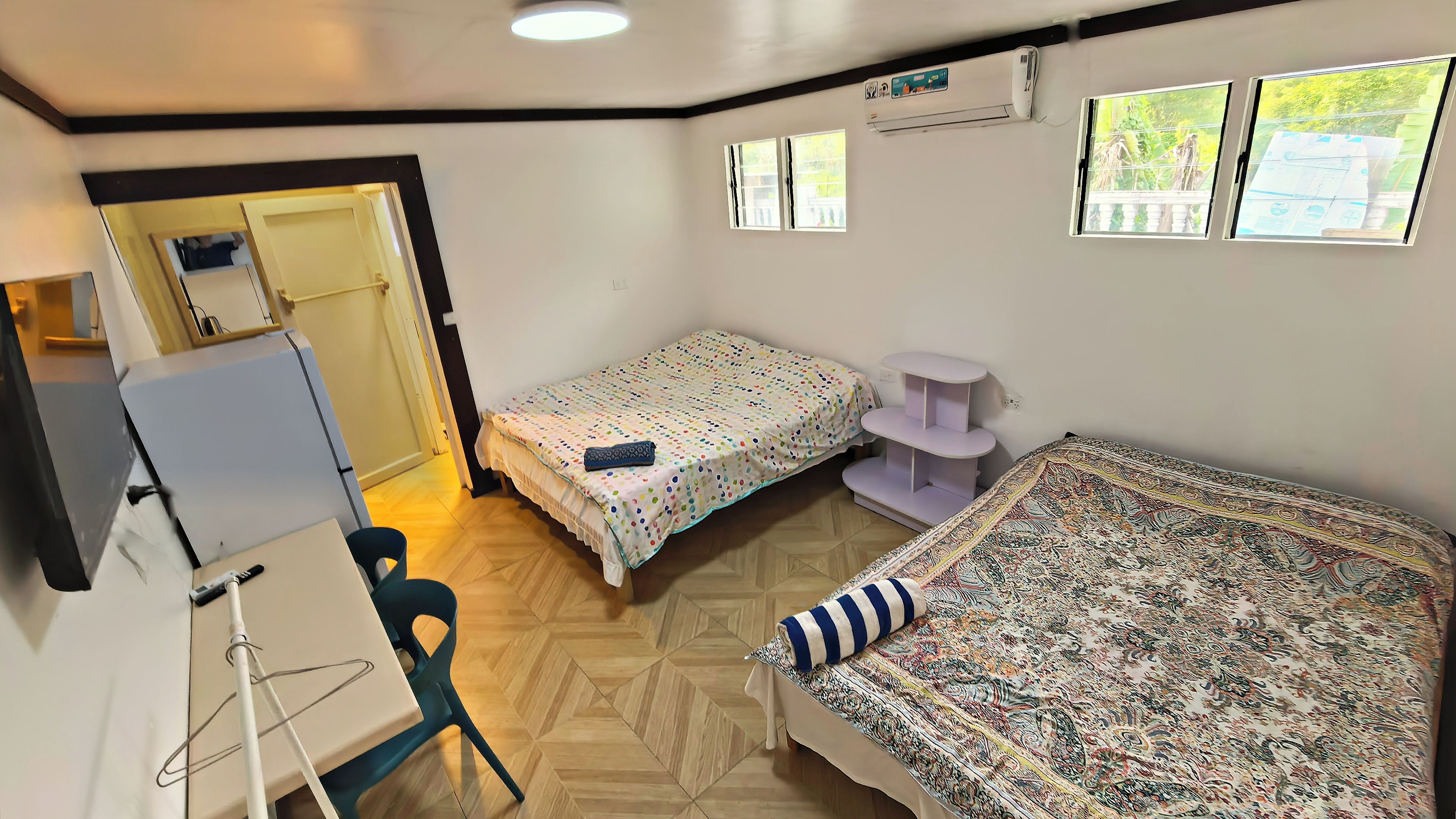 Une chambre avec deux lits, un bureau, une chaise et une fenêtre.