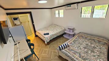 Une chambre avec deux lits, un bureau, une chaise et une fenêtre.