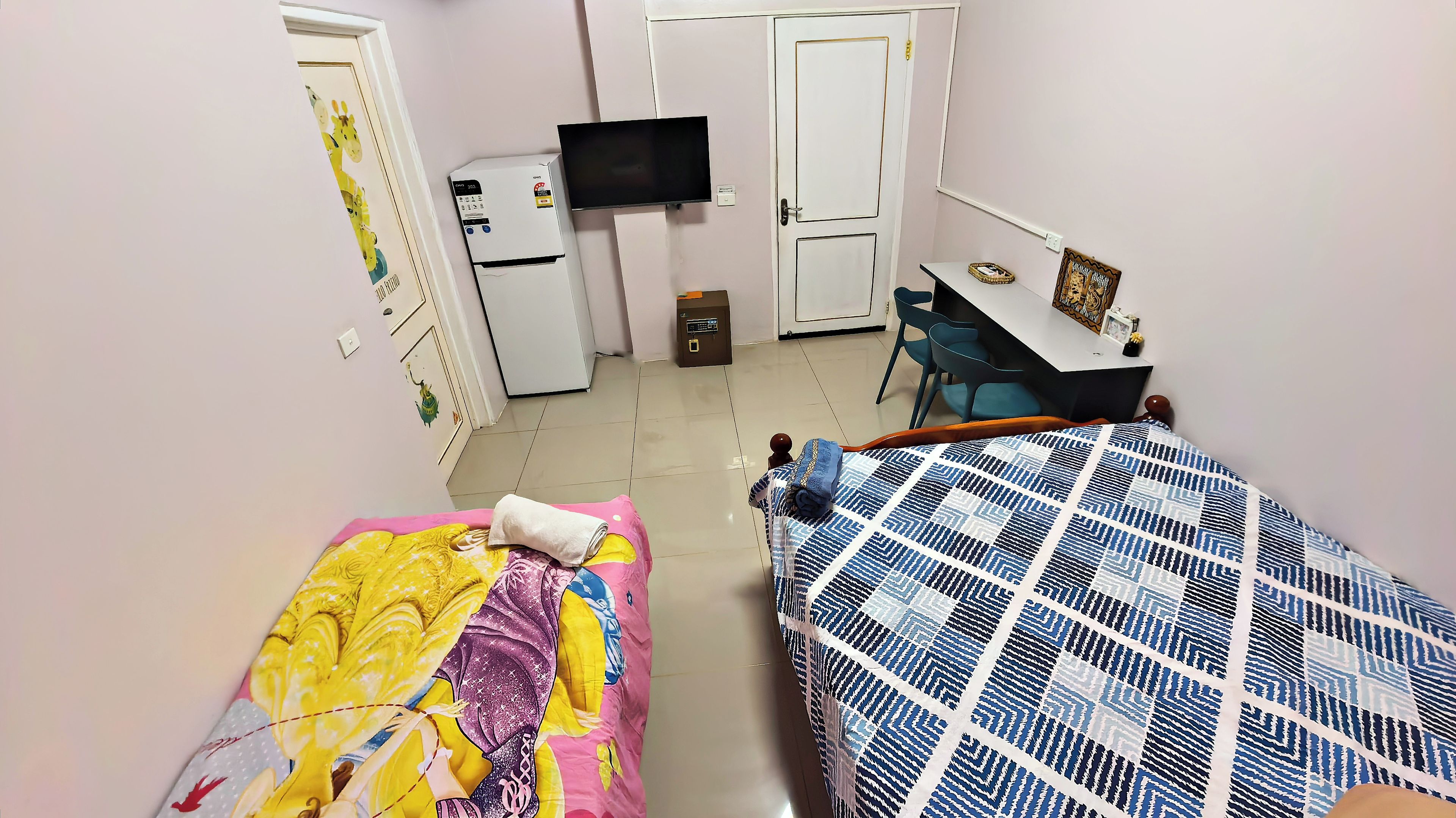 A room with two beds, a desk, a television, and a wardrobe.