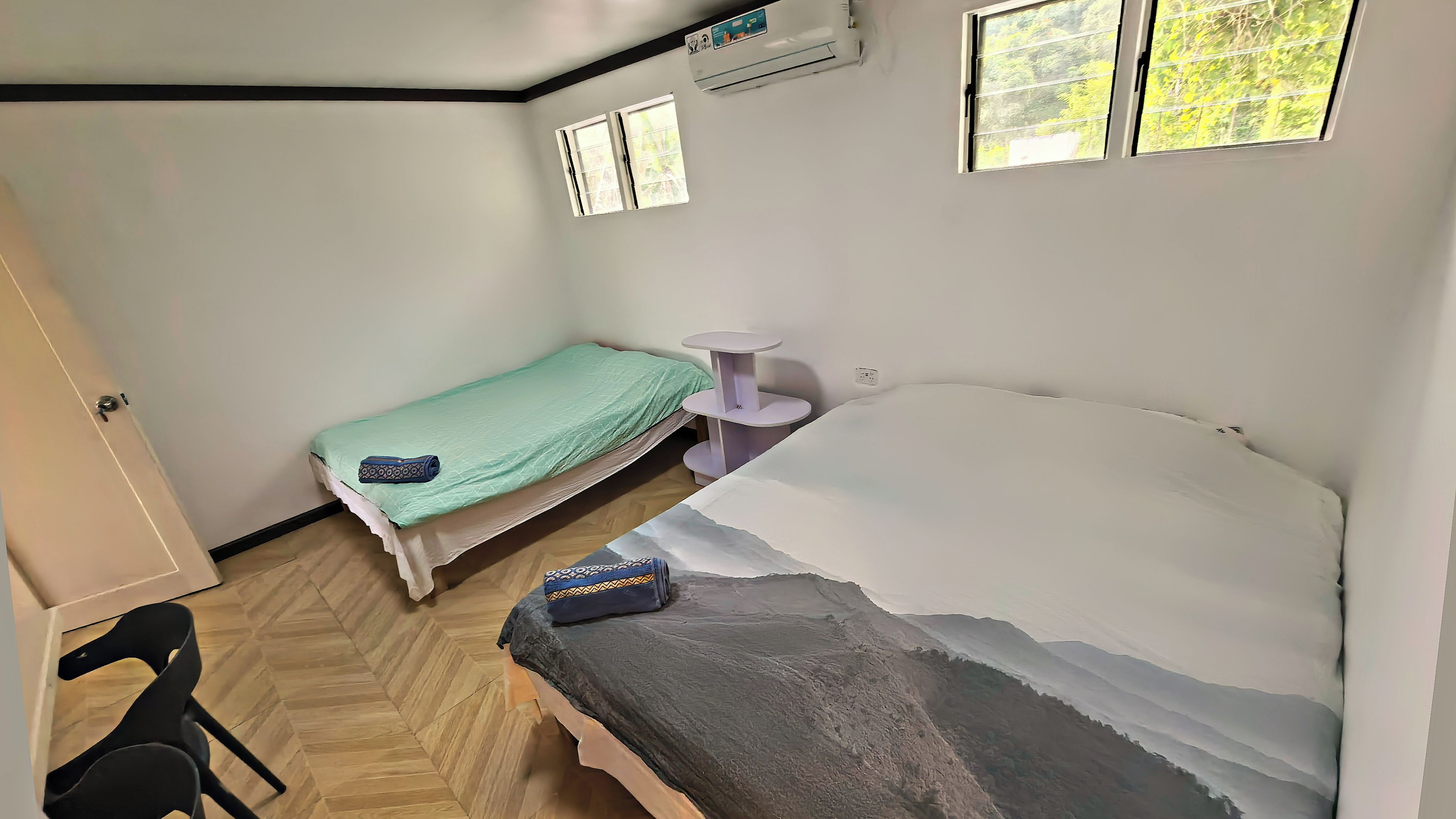 A room with two beds, a small table, and a window.