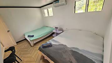 A room with two beds, a small table, and a window.
