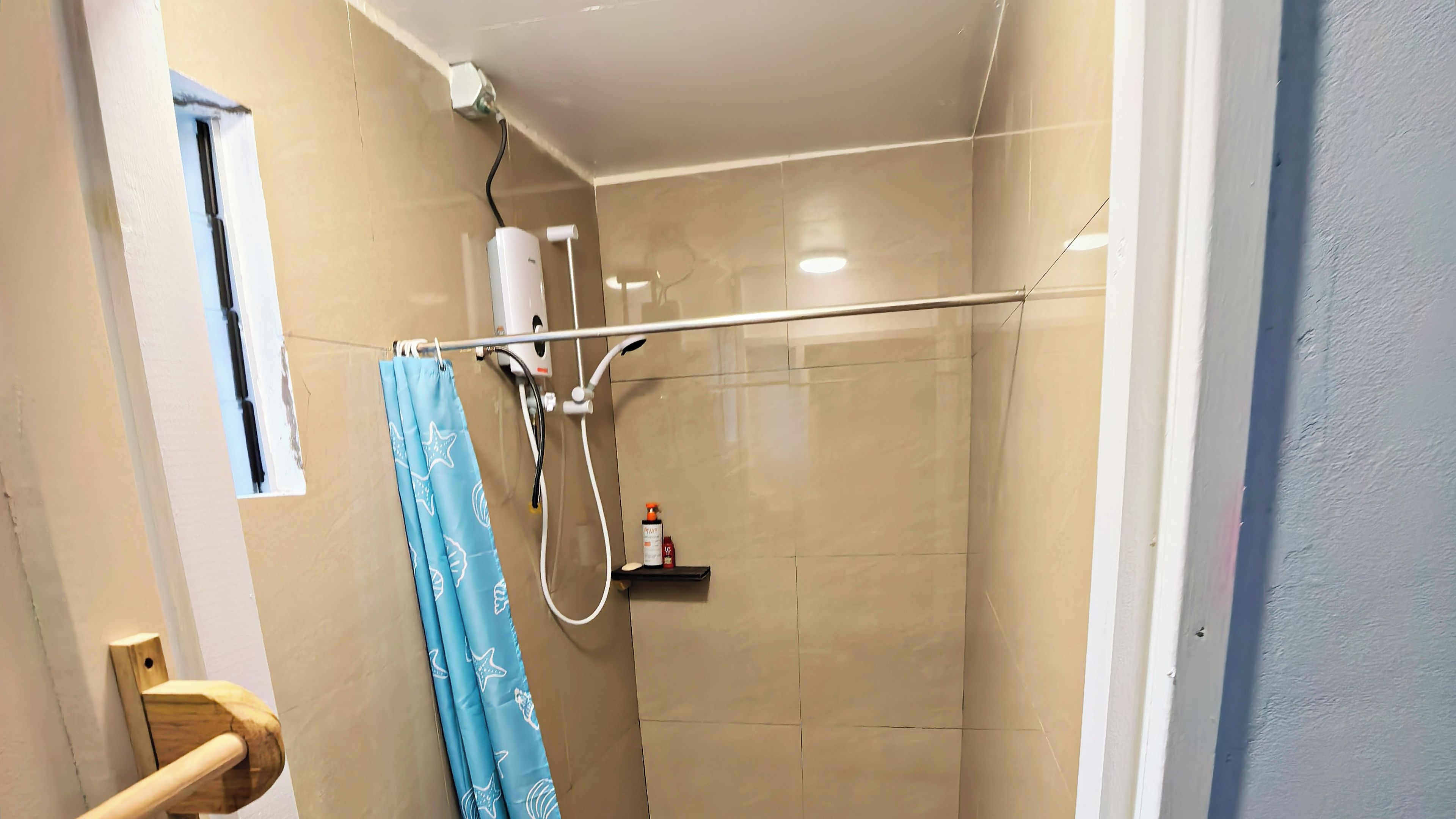 A bathroom with a shower, a towel rack, and a small shelf with toiletries.
