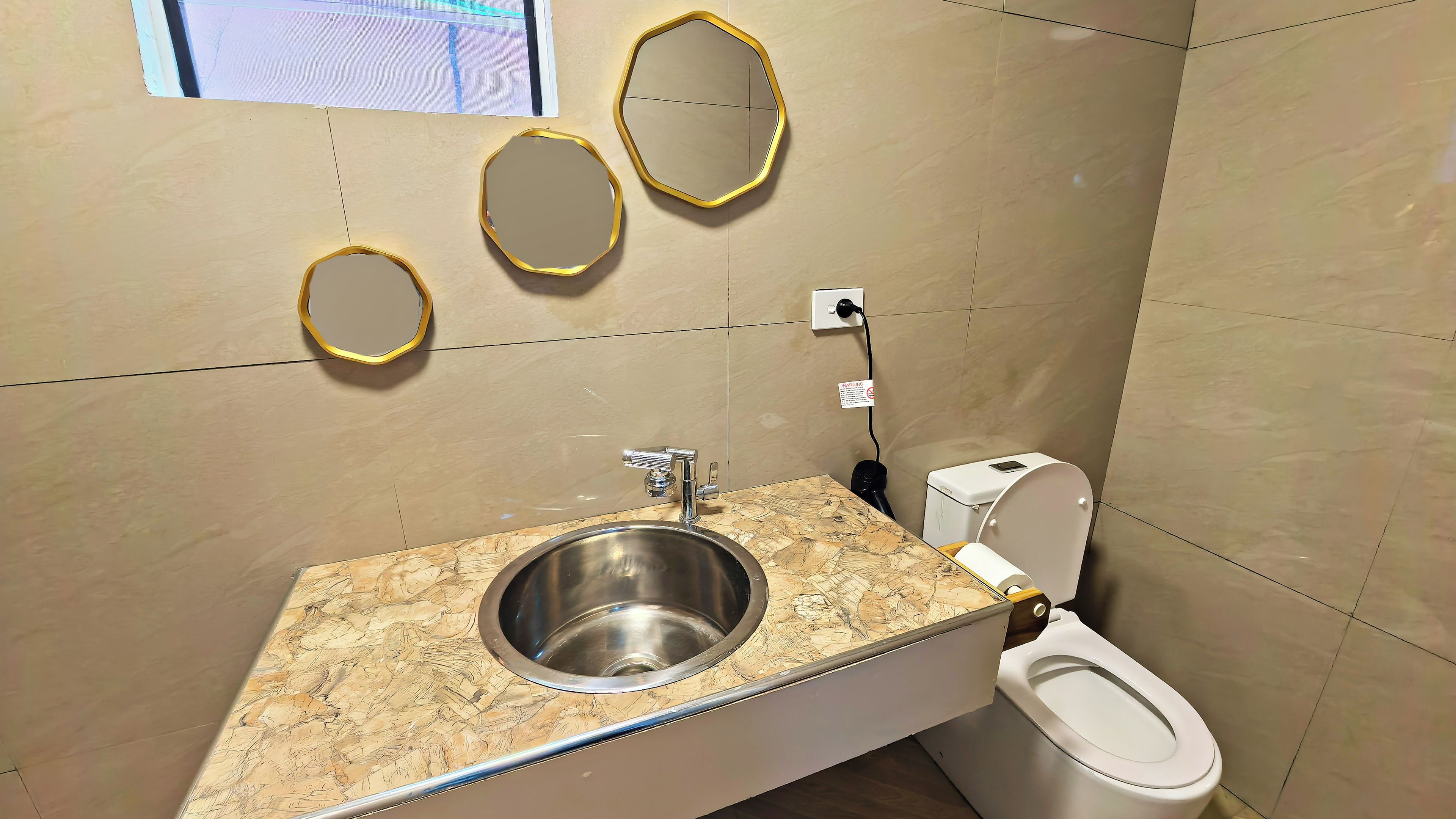 A bathroom with a marble countertop sink, a toilet, and three wall-mounted mirrors.