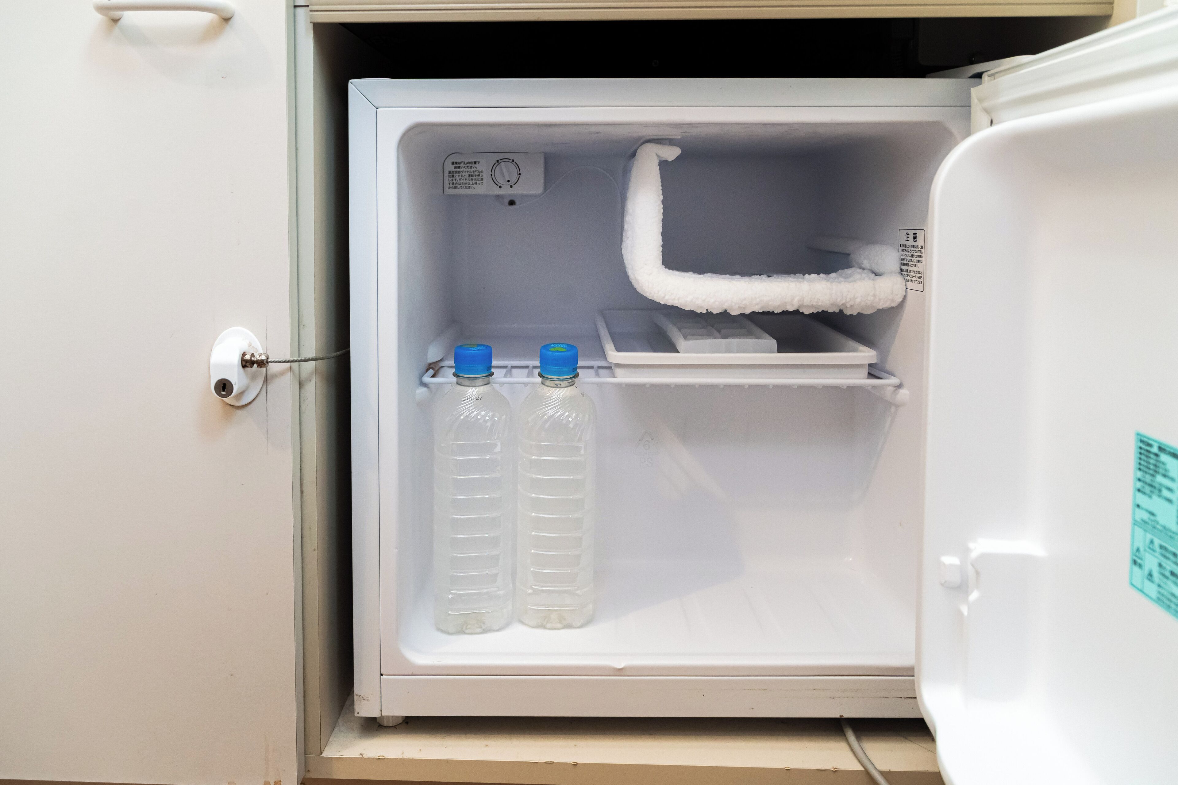 A refrigerator with two bottles of water and a control panel.