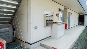 A building exterior with a covered entrance, a vending machine, and a utility box. - K HOUSE - E JOY INN Okubo Branch (Tokyo)
