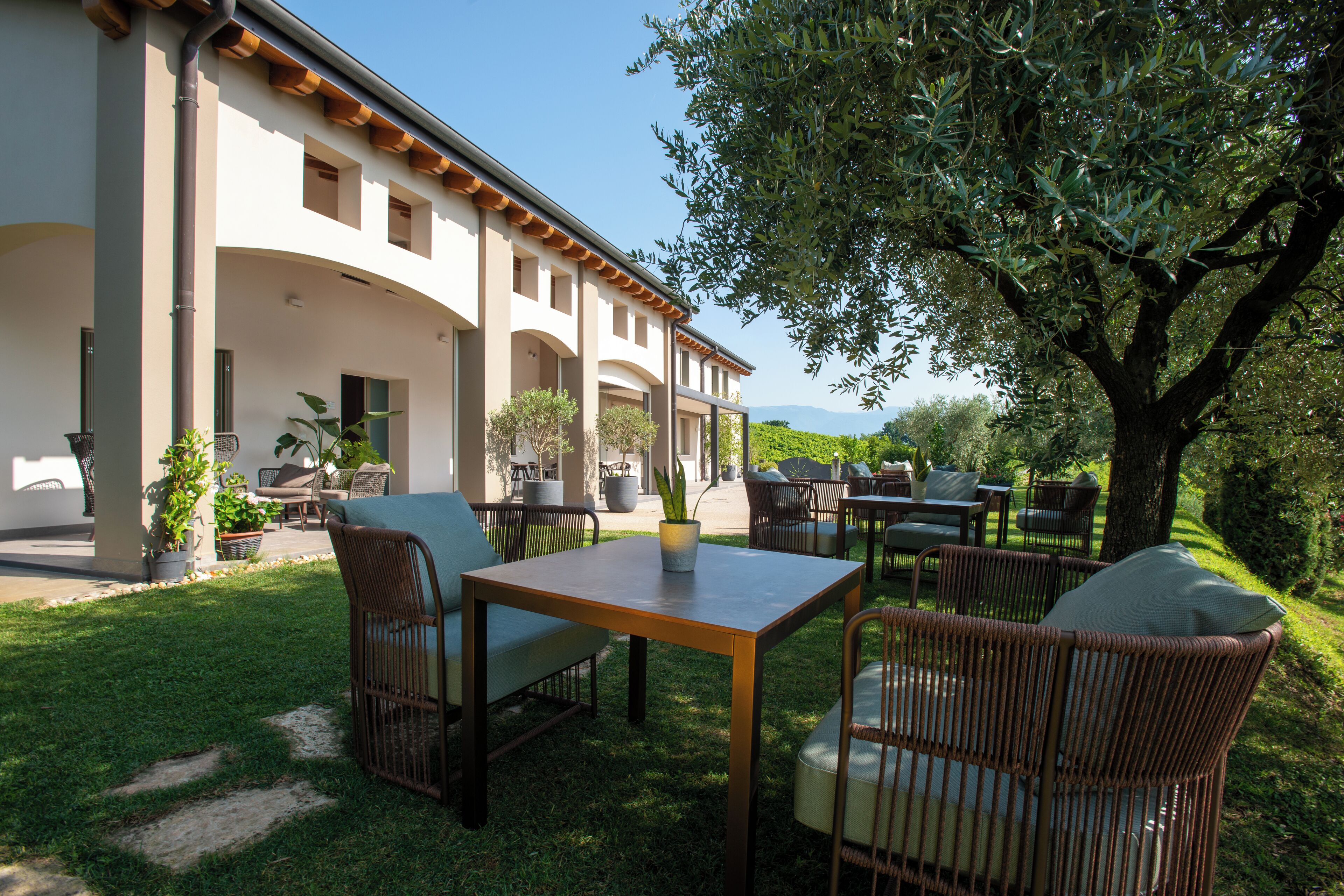 Un patio al aire libre con mobiliario de mimbre, una mesa y plantas en macetas.