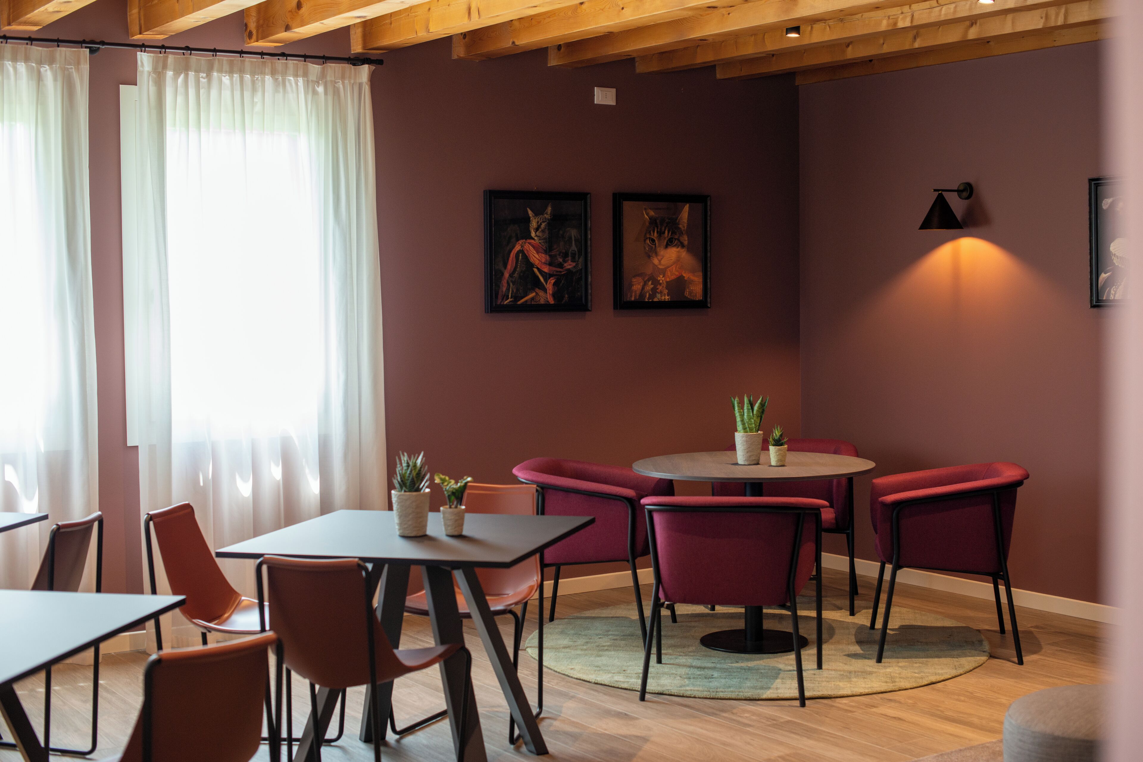 Un interior moderno con una mesa redonda, sillas rojas y techo de madera.