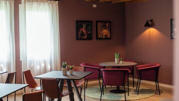 Un interior moderno con una mesa redonda, sillas rojas y techo de madera.