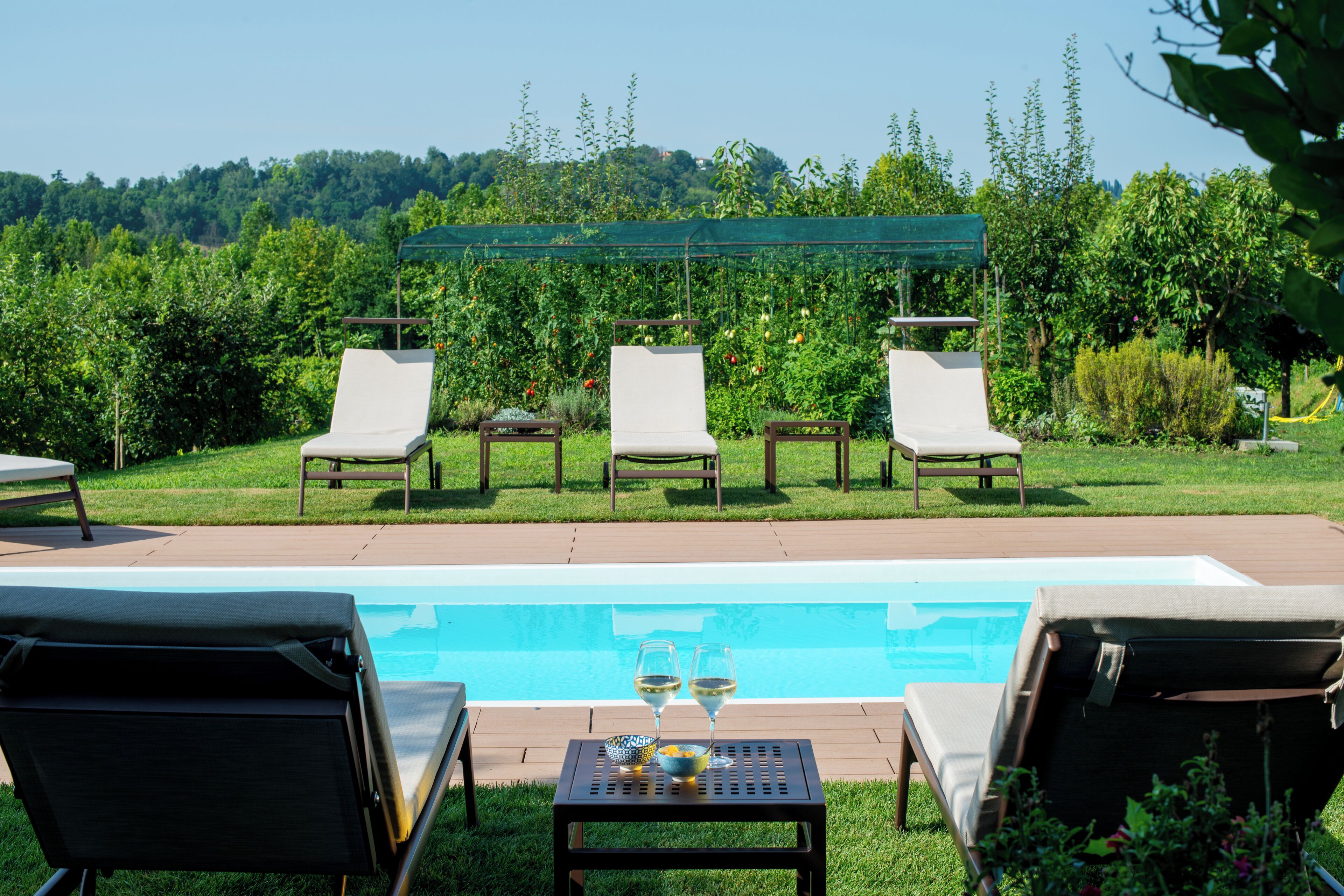 Ein Poolbereich mit Liegestühlen und einem Tisch mit Gläsern und einer Schüssel.