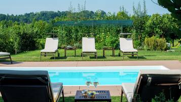 Ein Poolbereich mit Liegestühlen und einem Tisch mit Gläsern und einer Schüssel.