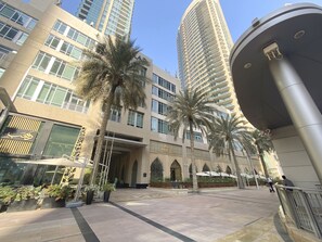 A modern hotel with a central courtyard, palm trees, and a large column. - Silkhaus Lofts, Downtown Dubai (Dubai)