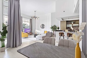 A modern living room with a grey sofa, a dining table, and a kitchen area in the background. - Silkhaus Lofts, Downtown Dubai (Dubai)