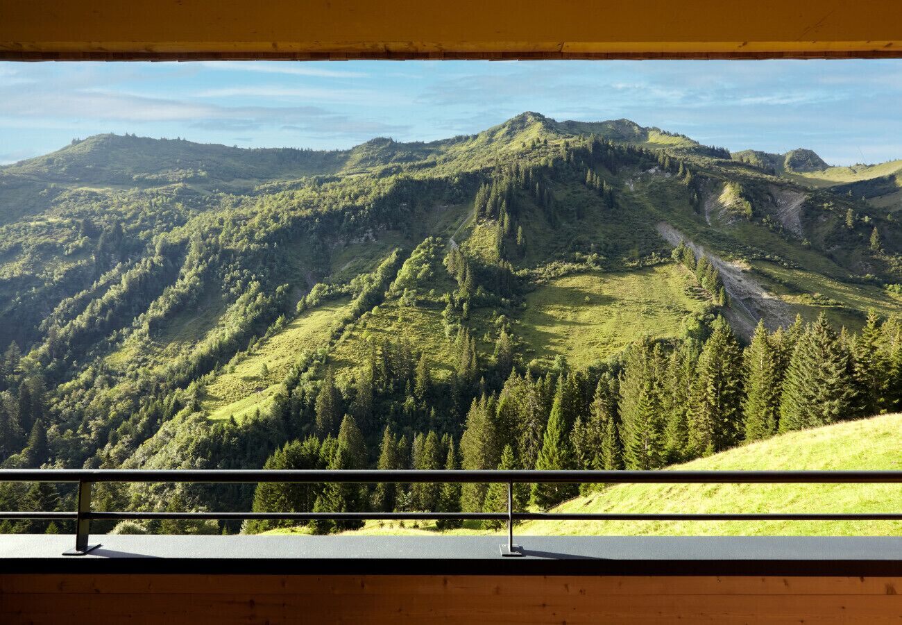 A mountain landscape viewed from a balcony with a metal railing.