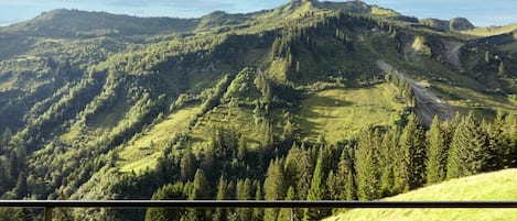 A mountain landscape viewed from a balcony with a metal railing.