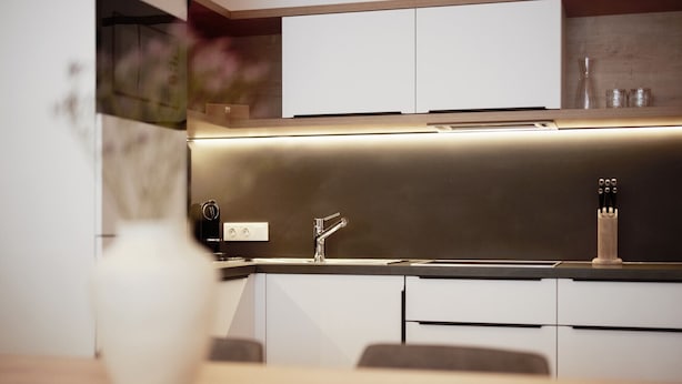 Uma cozinha moderna com bancada de aço inoxidável, forno embutido e pia com torneira moderna.
