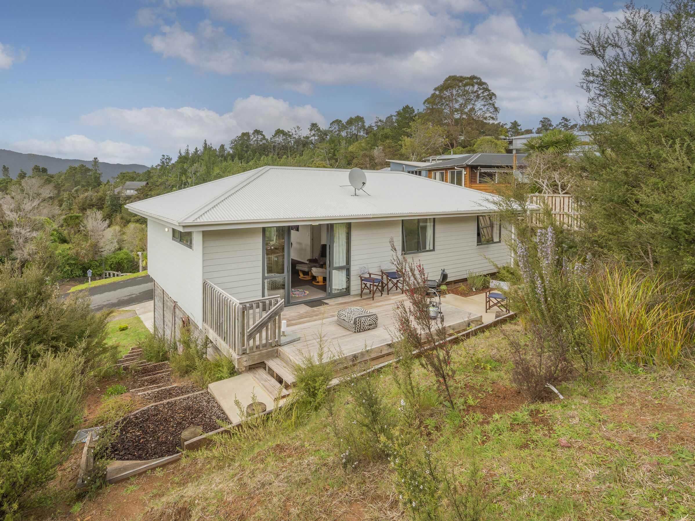 A single-story house with a covered porch, a satellite dish, and a small deck area.