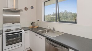 Eine moderne Küche mit einem Edelstahlherd, einem Geschirrspüler und einem Fenster mit Blick auf Bäume.