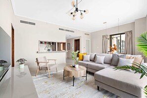 Een moderne woonkamer met een bank, salontafel en stoelen. Achtergrond is een keuken.