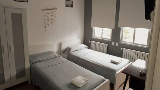 Et lille, enkelt værelse med to senge, et lille bord og en radiator.