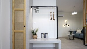 A modern interior with a white bench, a hanging light fixture, and a potted plant. - ONAR OURANOUPOLIS (Aristotelis)