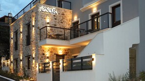 A modern two-story building with a stone facade, balconies, and outdoor lighting. - ONAR OURANOUPOLIS (Aristotelis)