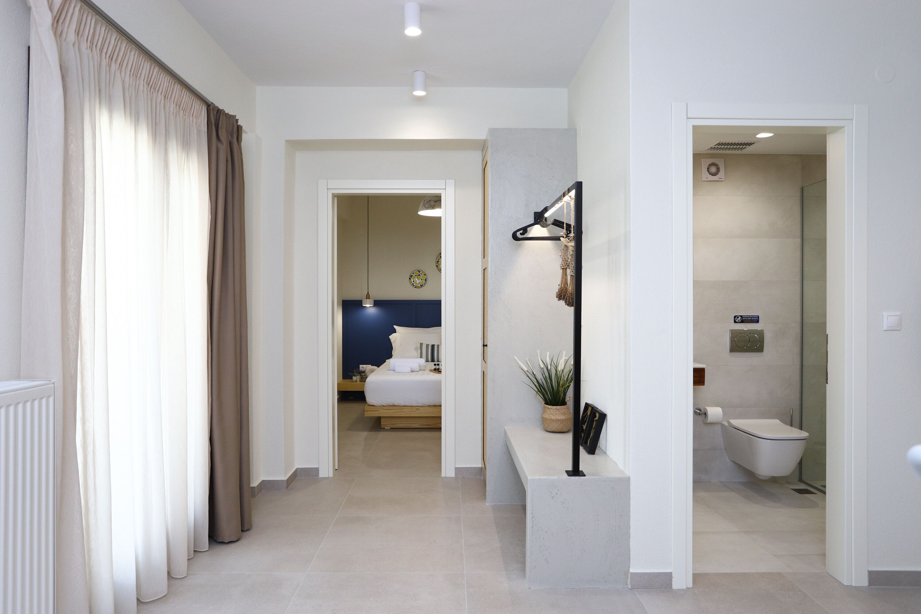 Una habitación de hotel moderna con cama, mesita de noche y baño con inodoro y ducha.