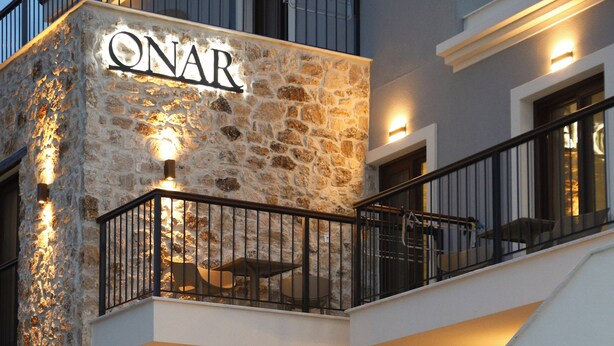 A two-story building with a stone facade and a balcony with a metal railing. - ONAR OURANOUPOLIS (Aristotelis)