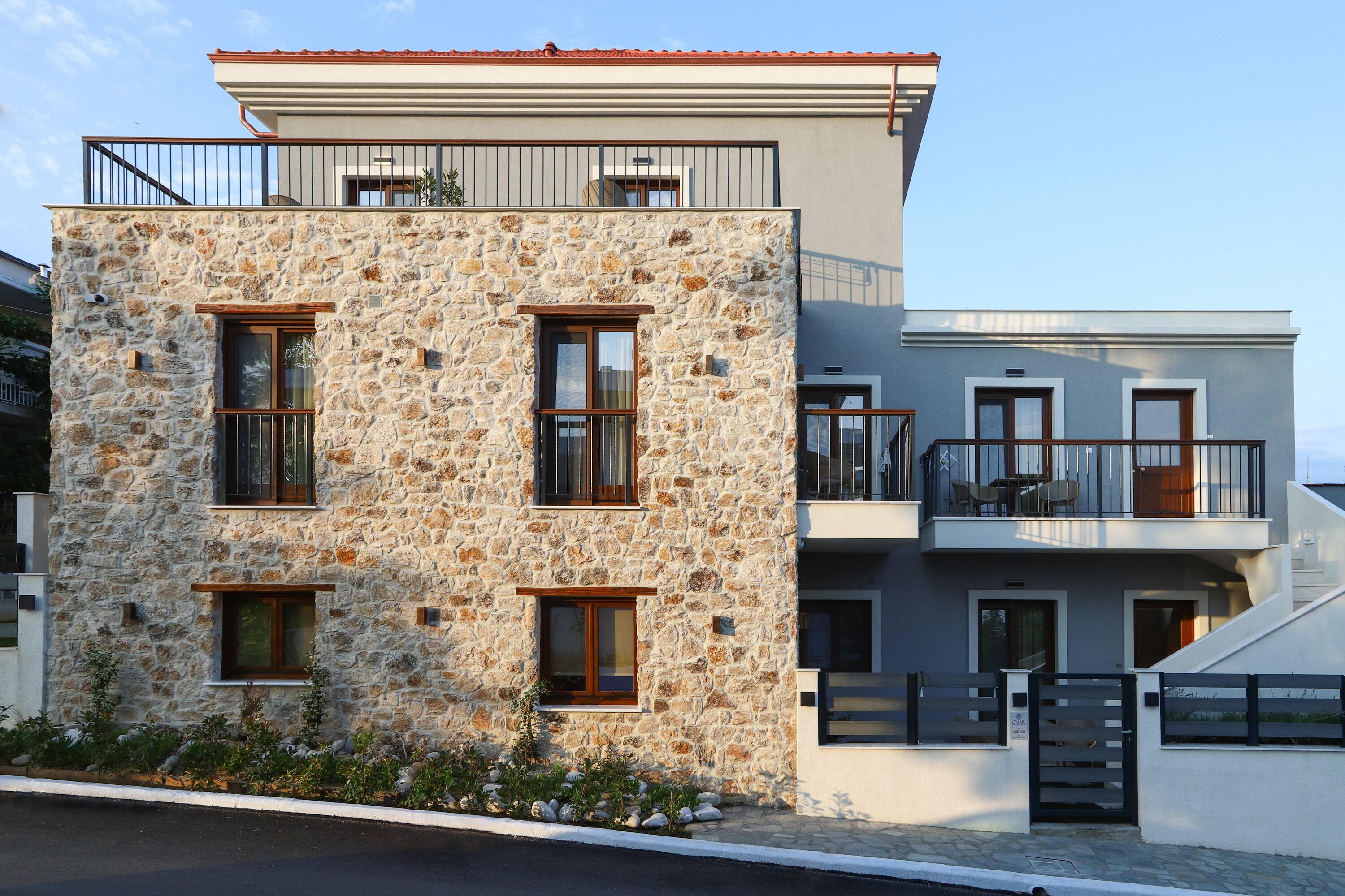 A modern two-story building with a stone facade and a balcony.