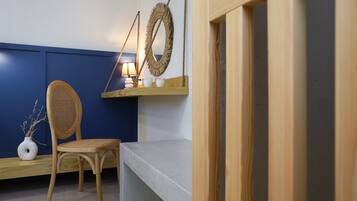 A room with a blue wall, a wooden chair, a white vase, a lamp, and a shelf with decorative items.