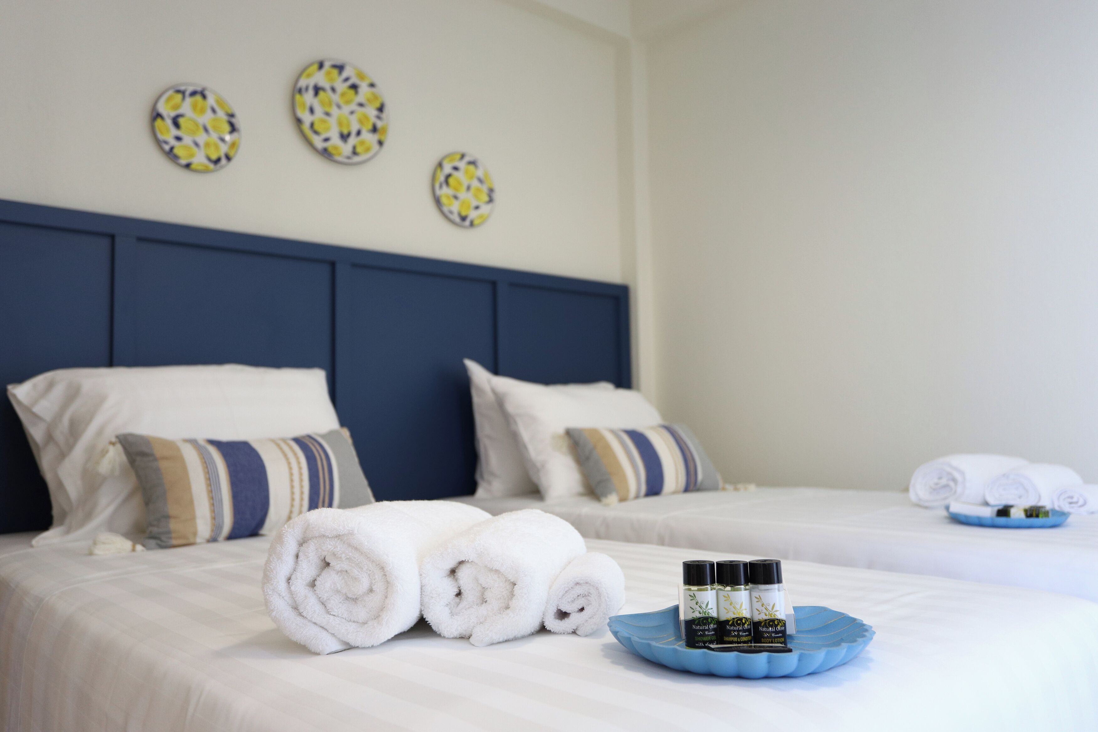 A hotel room with two beds, neatly made towels, and a tray with toiletries.