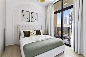 A modern hotel room with a large bed, a view of the city through a balcony, and a minimalist decor.