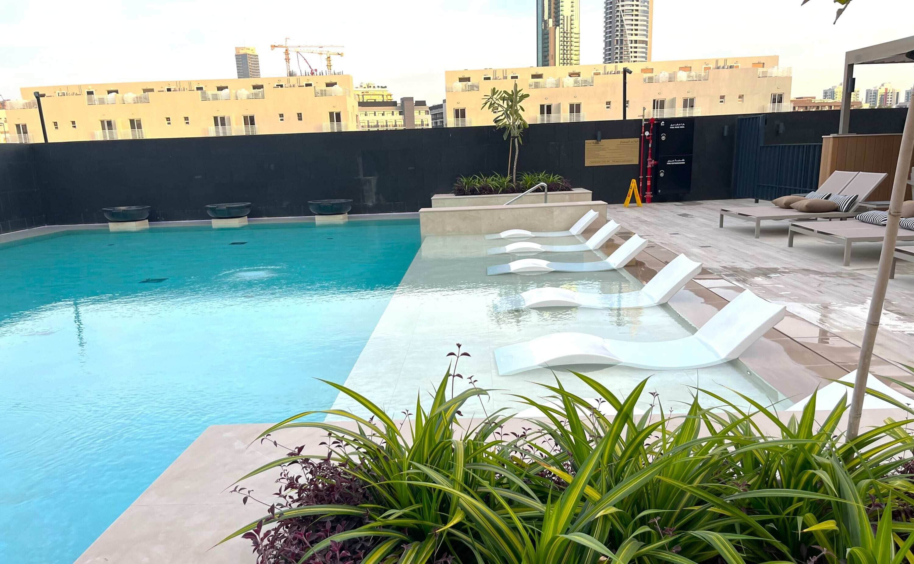 Une piscine sur le toit, agrémentée de chaises longues et de plantes.